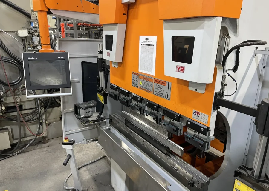 Close-up of a CNC press brake with its control screen and tooling